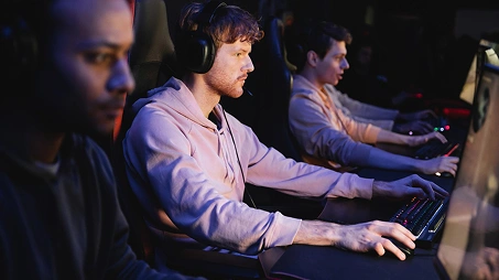 Geconcentreerde esports-spelers die op gaming-pc's met headsets strijden tijdens een intense multiplayer-wedstrijd.