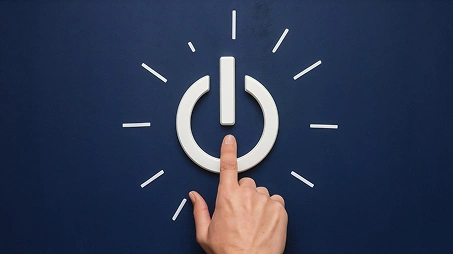 Een hand die op een oplichtend aan/uit-knopje drukt, symboliseert het opstarten van een computer, gameconsole of digitaal apparaat.